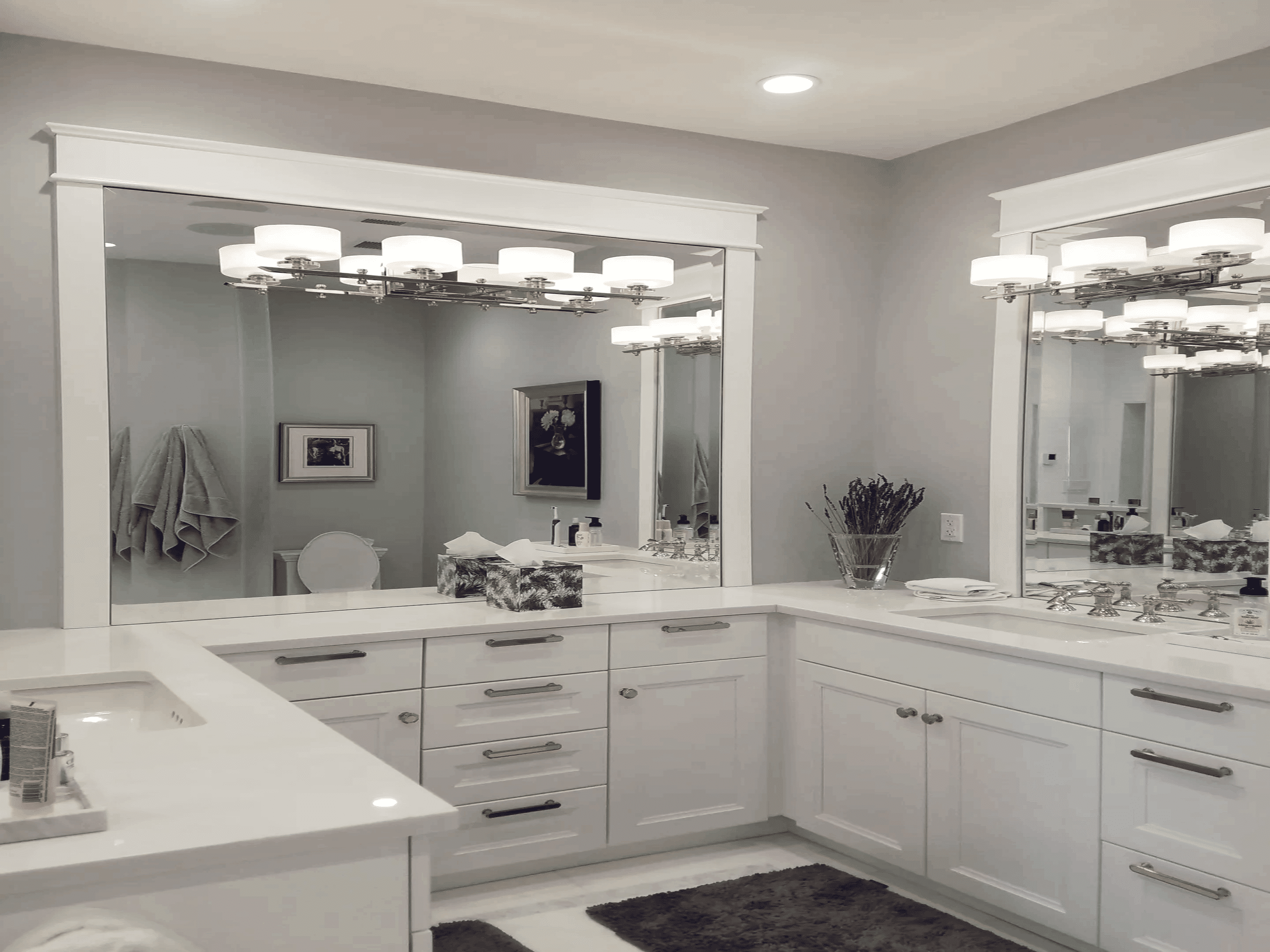 A bathroom vanity with large mirrors and a fresh, white aesthetic