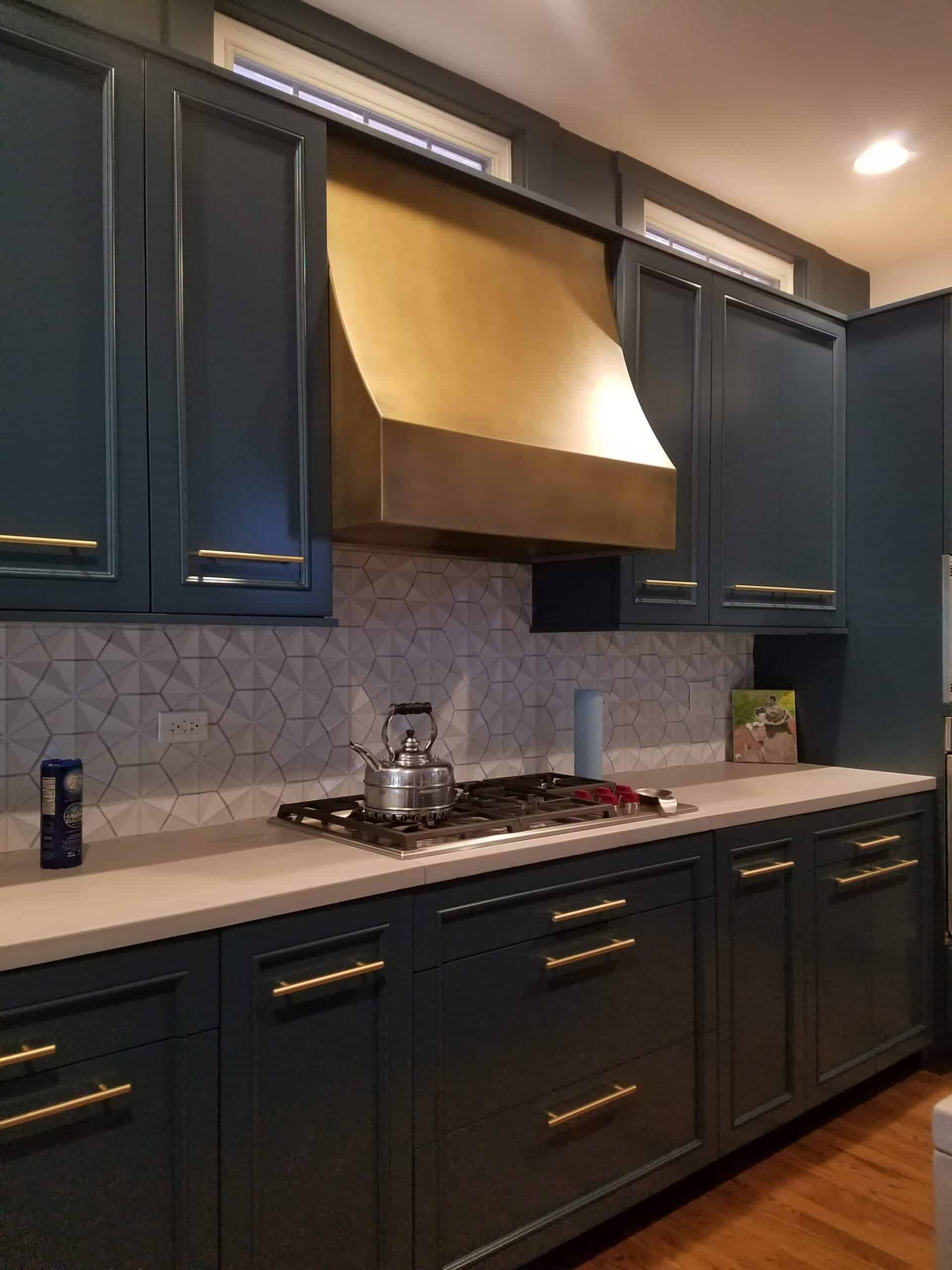 Sideview of a kitchen with dark blue cupboards and gold accents